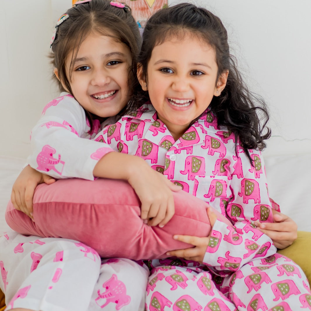 Bobo Girls Night Suit Set Two young girls sitting close together, smiling, wearing matching pink night suits with animal character designs.
