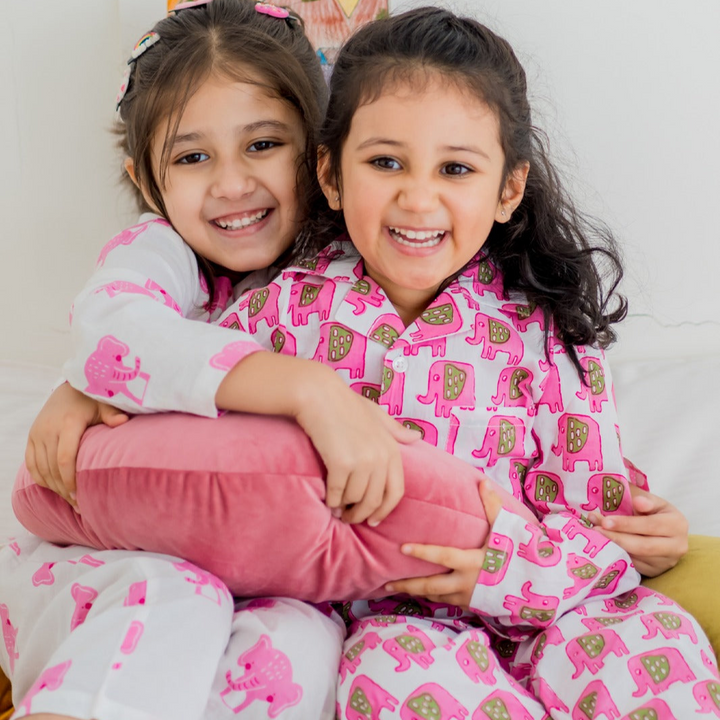 Bobo Girls Night Suit Set Two young girls sitting close together, smiling, wearing matching pink night suits with animal character designs.