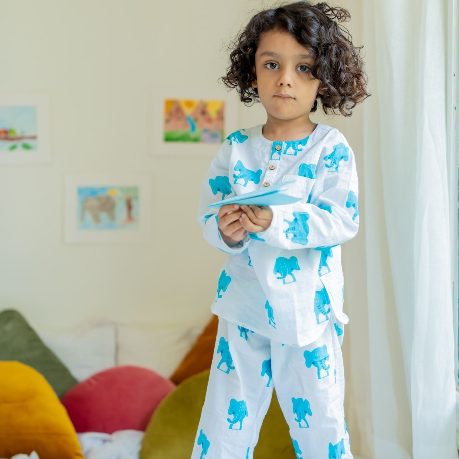 Dumbo Night Suit Set A child standing in a room wearing a long-sleeved white night suit with blue elephant prints, featuring a round neckline and full sleeves.