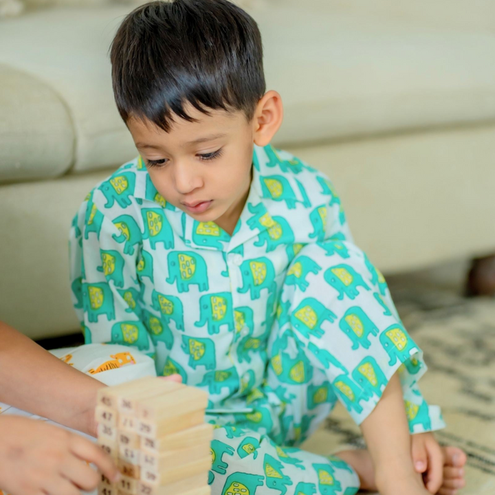 Ellie Night Suit Set A boy sitting on the floor engaged with a toy, wearing a green night suit set with elephant prints.