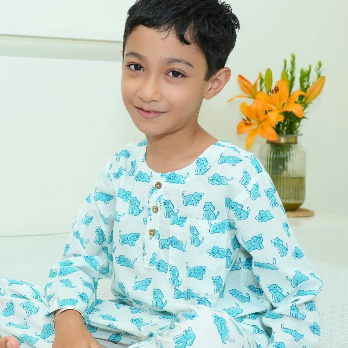Good Doggo PJ set klephant night suit
Child wearing a light blue pajama set with animal patterns, sitting indoors.