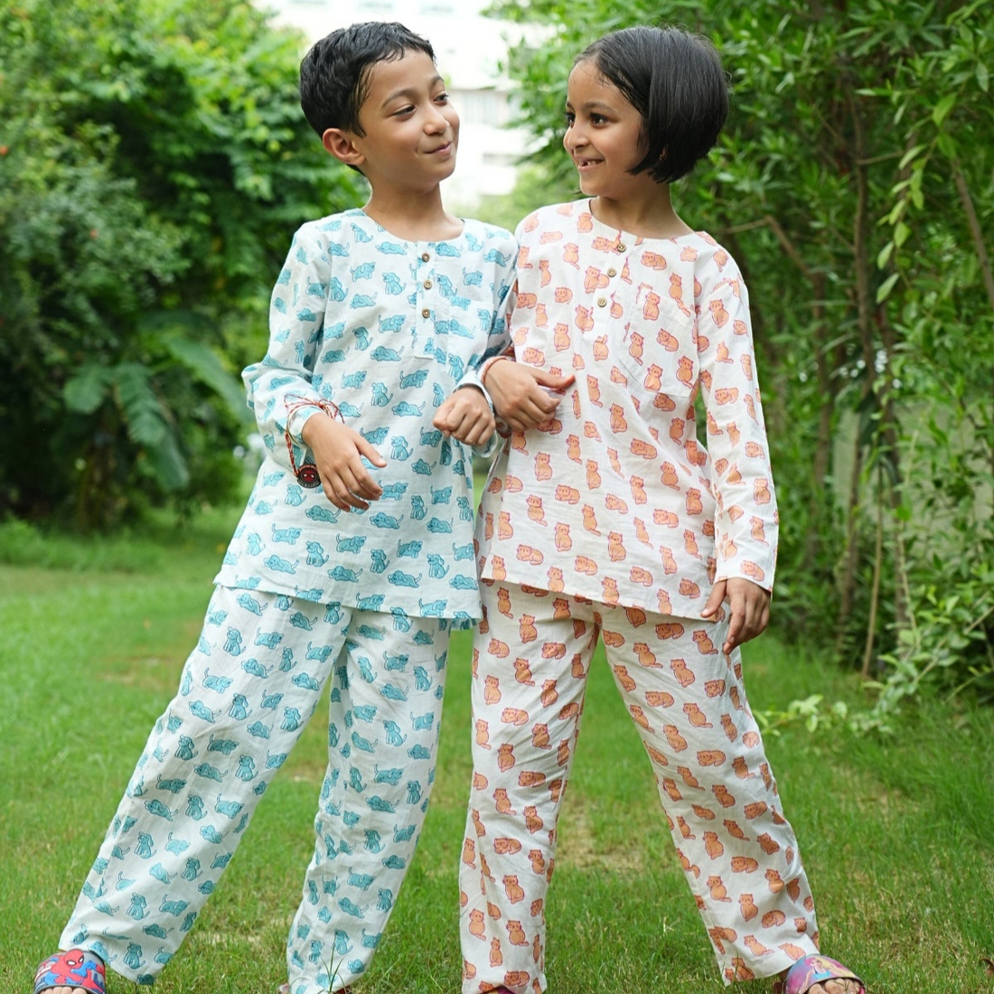 Meow Mornings PJ set night suit Two children in matching pajama sets standing outdoors on grass with trees in the background
